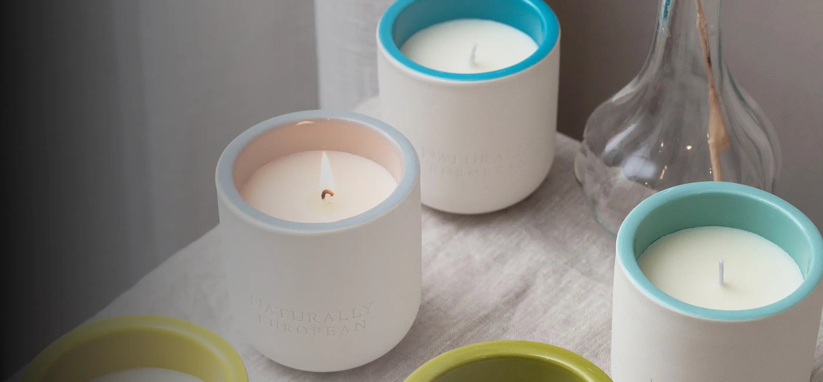 Set of small candles in colorful holders on a textured surface.