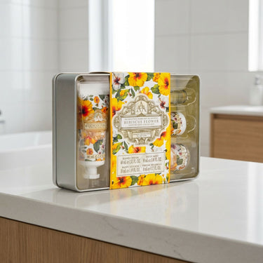 Hand cream set with floral packaging in a decorative tin on a bathroom counter.