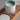 White candle in a ceramic holder with a blue rim on a wooden surface, branded 'Naturally European'.