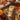 A tube of Orange Blossom hand and foot care product sits on a rustic wooden surface surrounded by autumn leaves, acorns, a small pumpkin, a knit blanket, and a cup, creating a cozy fall-themed flat lay.