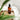 Bottle of 'Repair the air' toilet drops on a wooden board with a white towel and green leaves in the foreground.