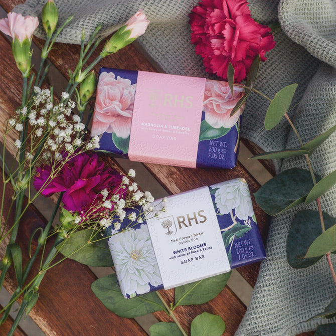 Three soap bars with floral designs on a wooden surface with flowers and leaves.