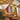 A boxed lip gloss trio from Somerset & toilestry called Time to Shine, displayed on a kraft paper background with holiday decorations. The box contains three tubes of lip gloss in red, purple, and green, tied with a gold ribbon.