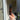 Hand holding a bottle of RHS Tomato Leaf body mist in front of a door.