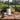 Gardening tools and products on a wooden table with an outdoor garden setting.
